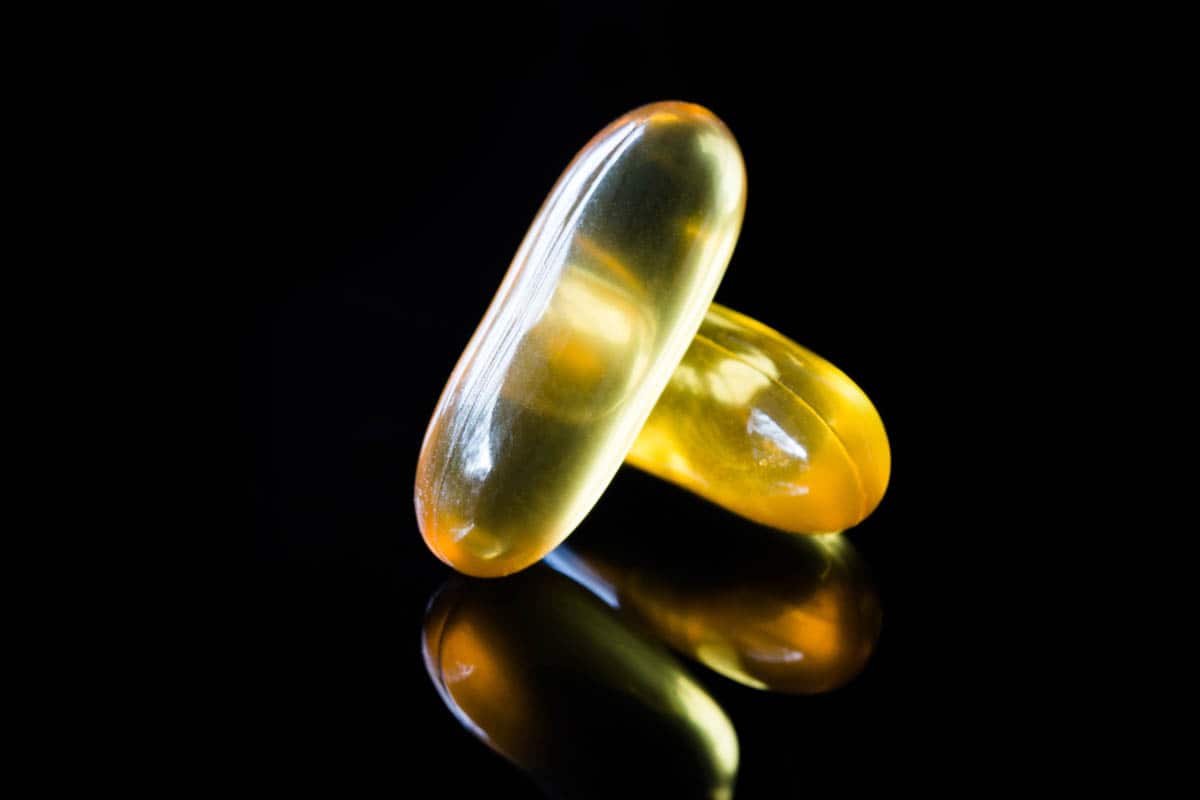 Syndrom DDA, współuzależnienie i moja tożsamość – jak ją znaleźć? - dwie żółte pigułki na czarnym tle - artykuł Marity Woźny